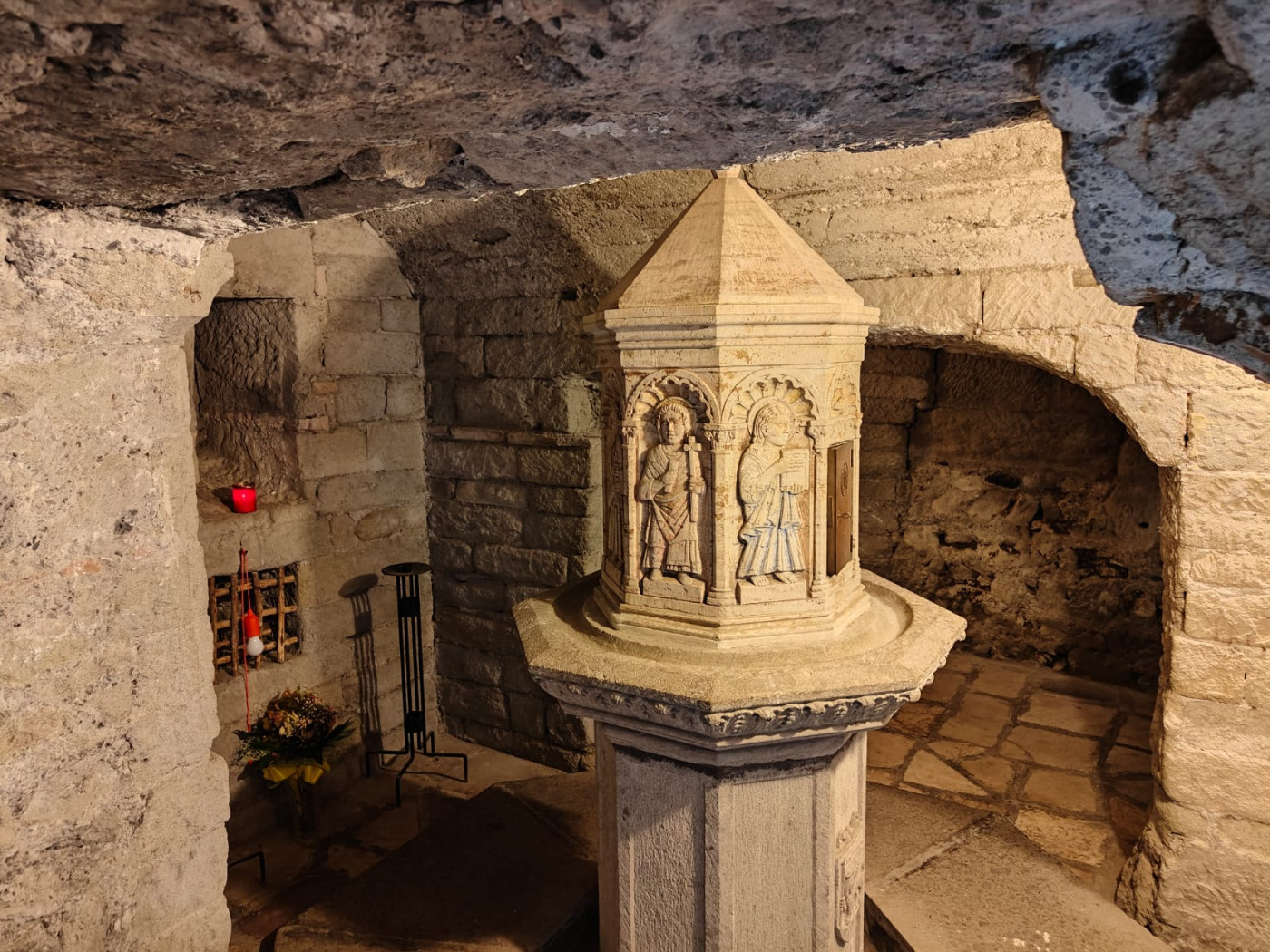 Il suggestivo interno della cripta romanica a deambulatorio, con il fonte battesimale e i blocchi in pietra a vista