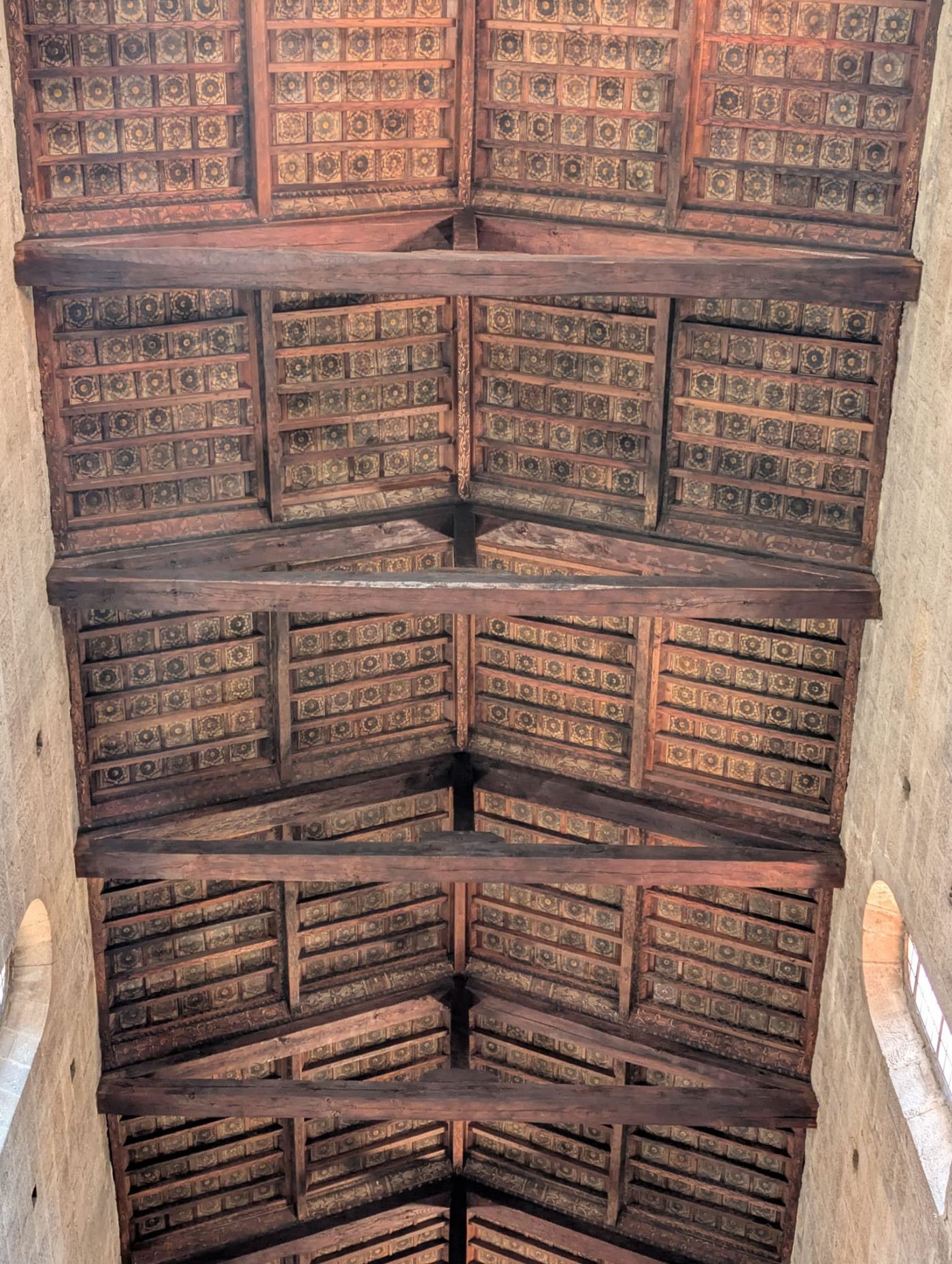 Dettaglio dal basso del soffitto ligneo a capriate le travi in castagno e le migliaia di pianelle in cotto finemente dipinte e decorate formano un soffitto a cassettoni di eccezionale pregio storico